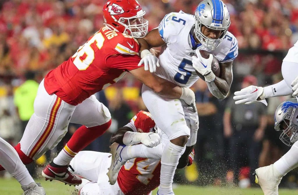 Two NFL players in tackle motion on the field.